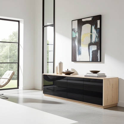 A modern sideboard cabinet with glossy black doors and a light wood frame, styled in a minimalist room with an abstract painting on the wall.