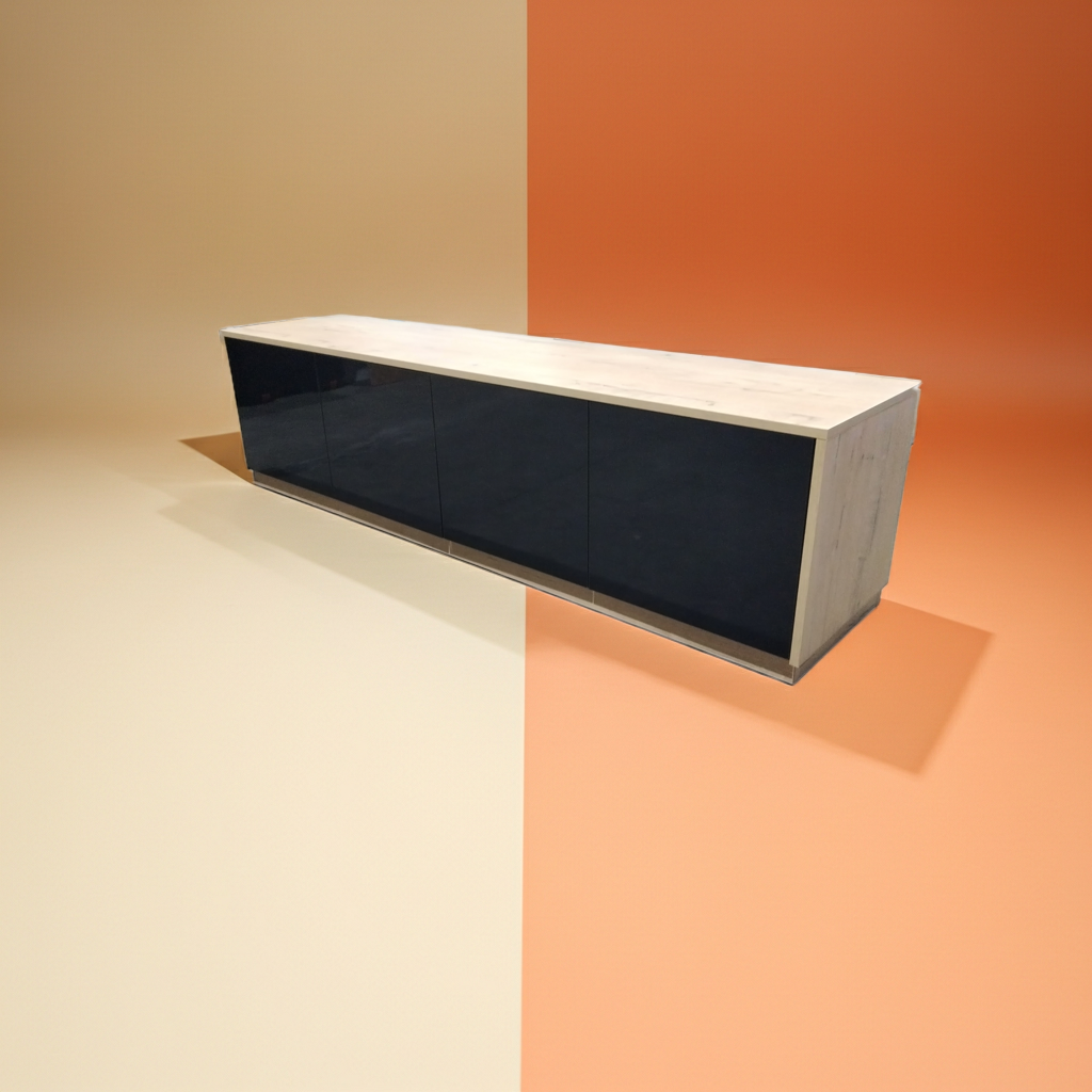 A modern rectangular sideboard or console cabinet with glossy black front panels and a light wood grain top and side panels, shown floating against a split beige and orange studio background.