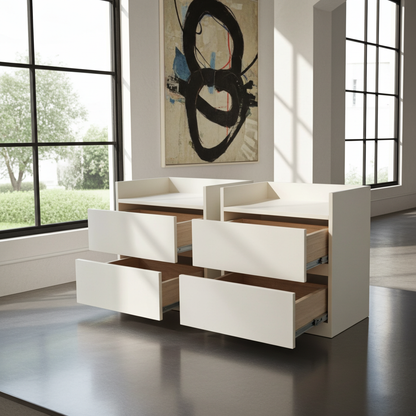 A modern white dresser with multiple drawers partially open, shown in a bright, contemporary room with large windows and a wall art piece behind it.